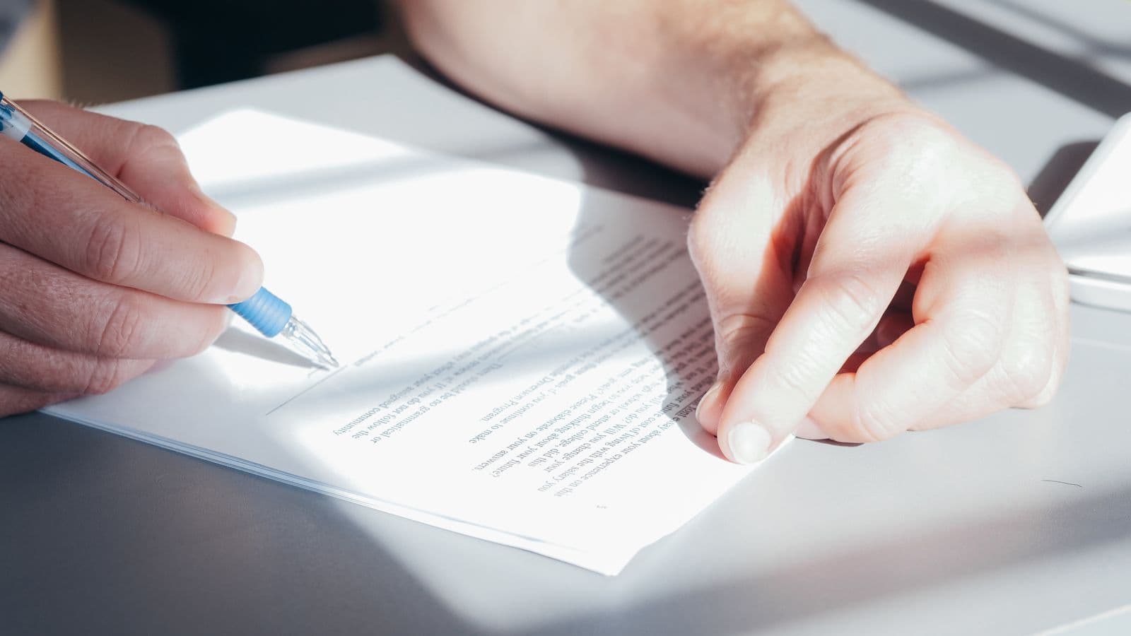 Hands reviewing and signing a contract